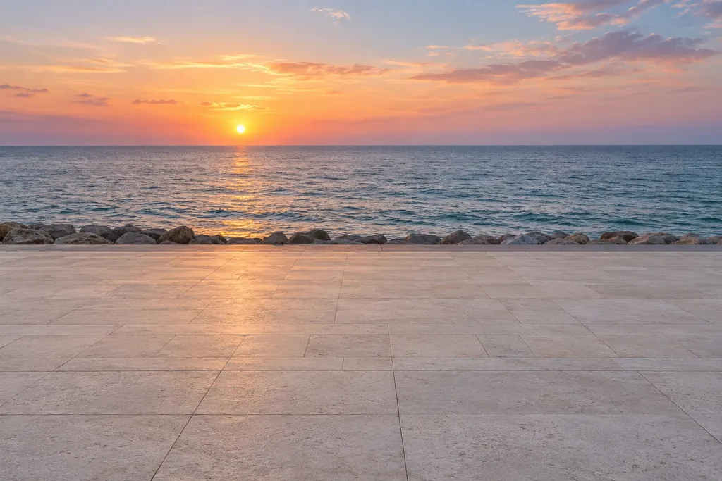 A stone promenade facing the sea as the sun sets on the horizon